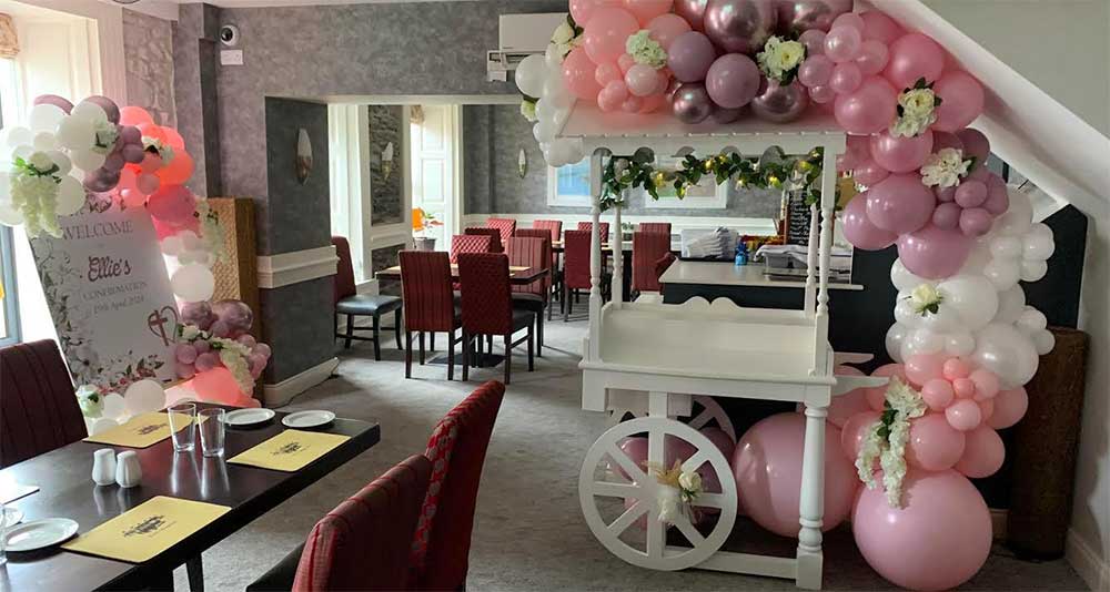 Green, silver and white balloon arch and table balloons by Sweet Times for a confirmation party in a hotel function room